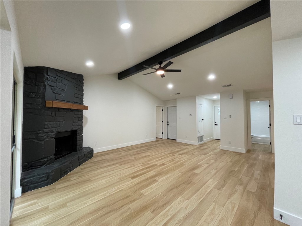 an empty room with wooden floor fireplace and windows