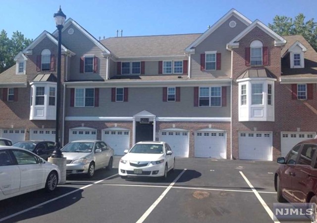 a front view of a building with cars parked