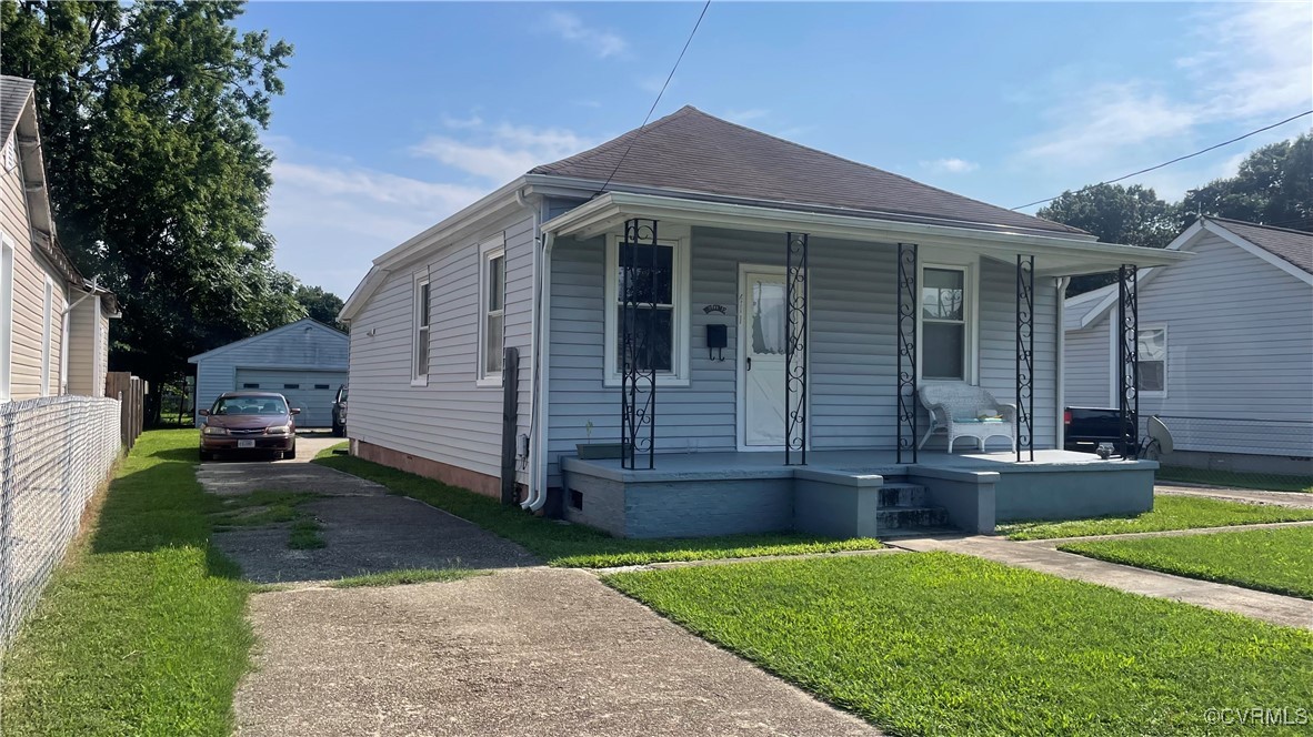 Bungalow with covered porch, a garage, an outbuild