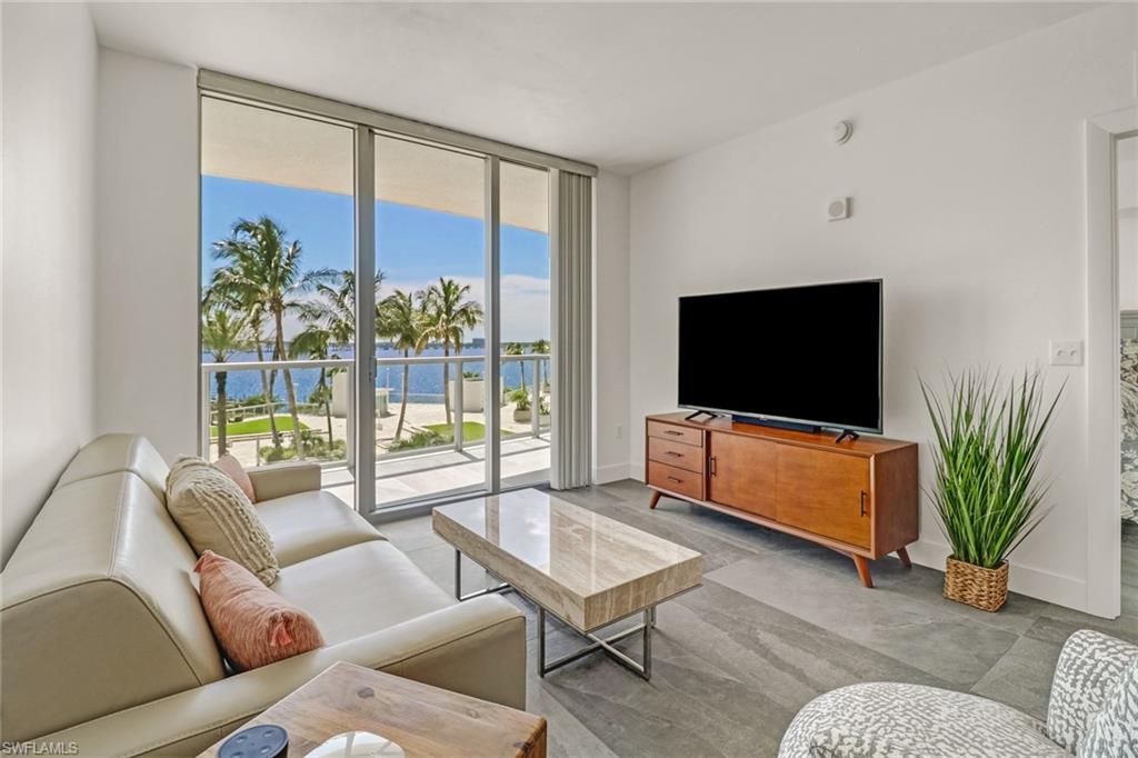 a living room with furniture a flat screen tv and a floor to ceiling window