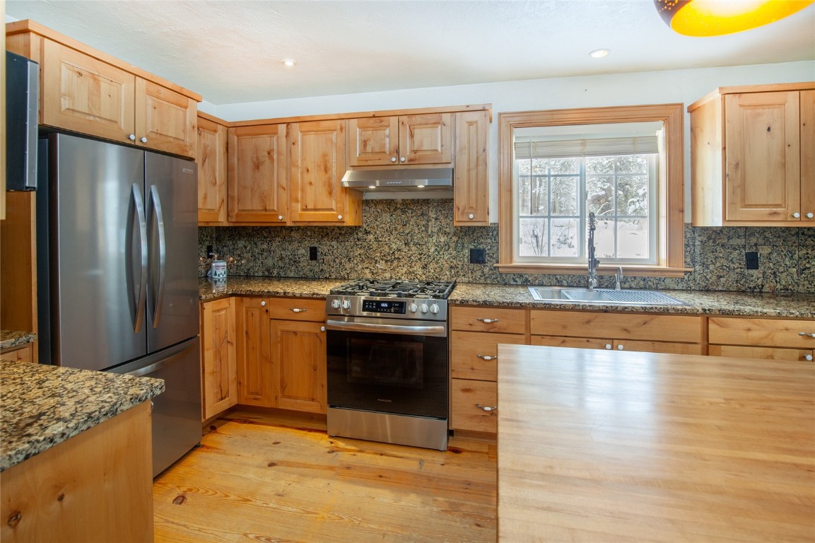 a kitchen with stainless steel appliances granite countertop a refrigerator a stove and a sink