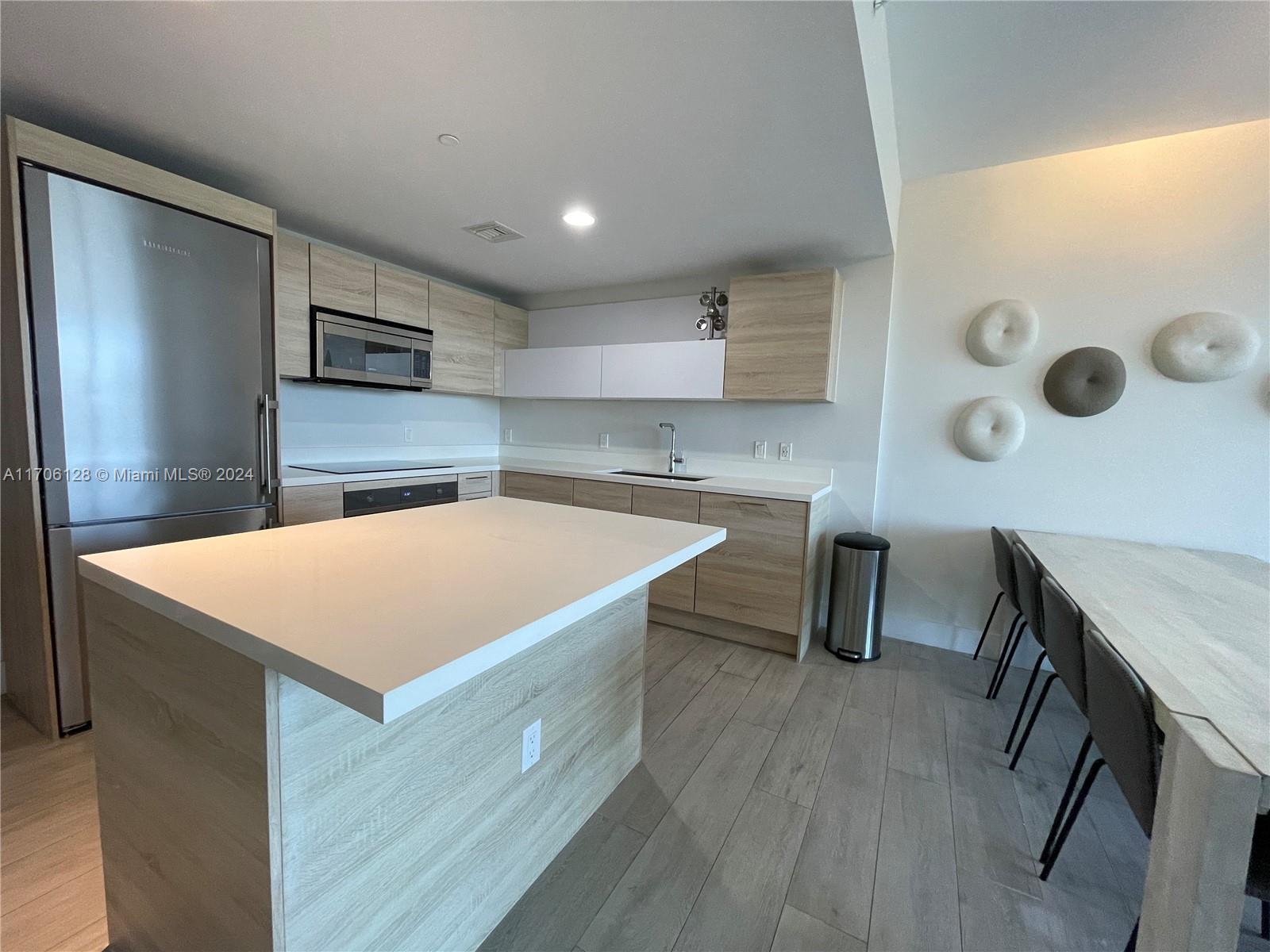 a kitchen with stainless steel appliances a table chairs and a refrigerator