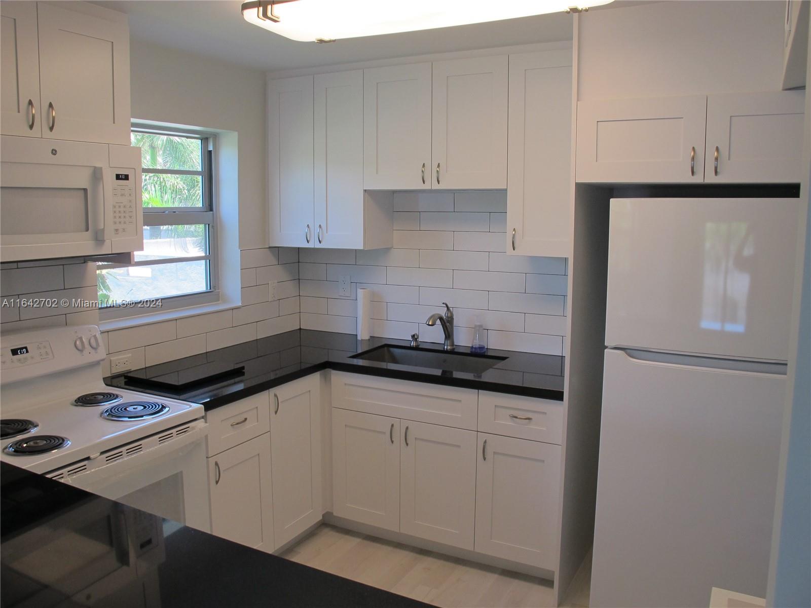 a kitchen with granite countertop a sink cabinets and stainless steel appliances