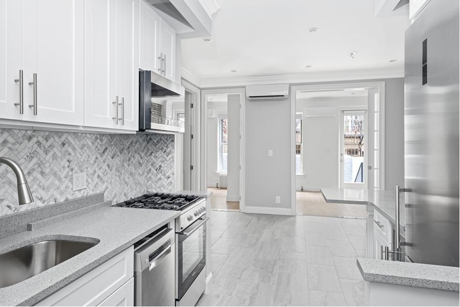 a kitchen with stainless steel appliances granite countertop a sink and a refrigerator