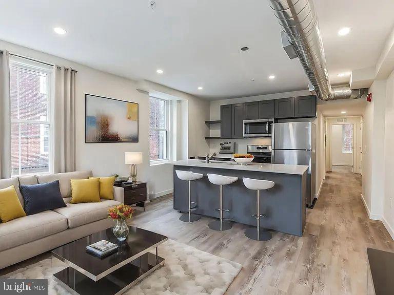 a living room with stainless steel appliances kitchen island granite countertop furniture a rug kitchen view and a chandelier