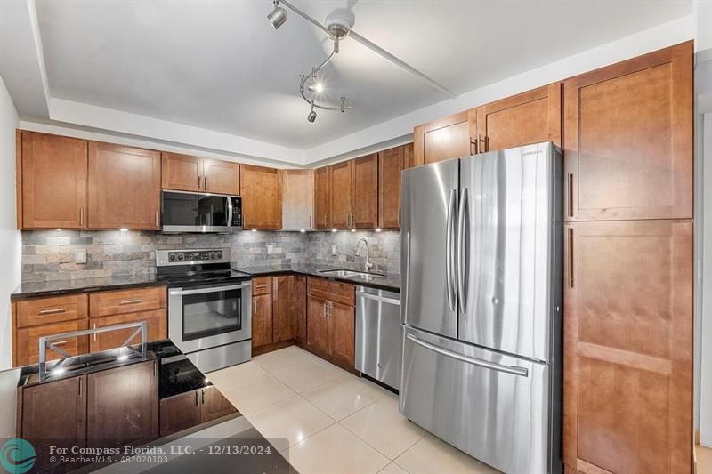 a kitchen with stainless steel appliances granite countertop a refrigerator stove microwave and sink