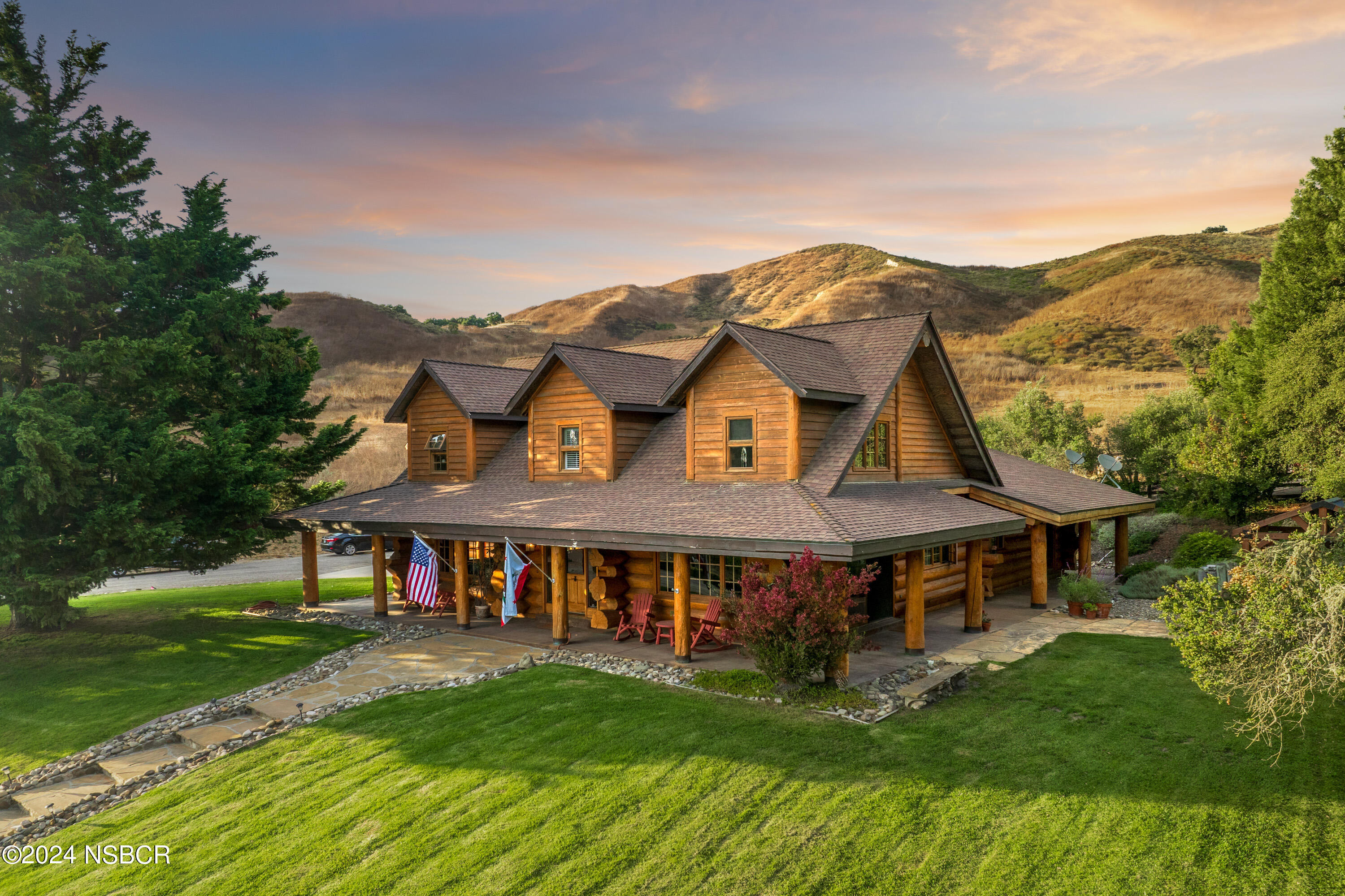 a view of a big house with a big yard and large trees