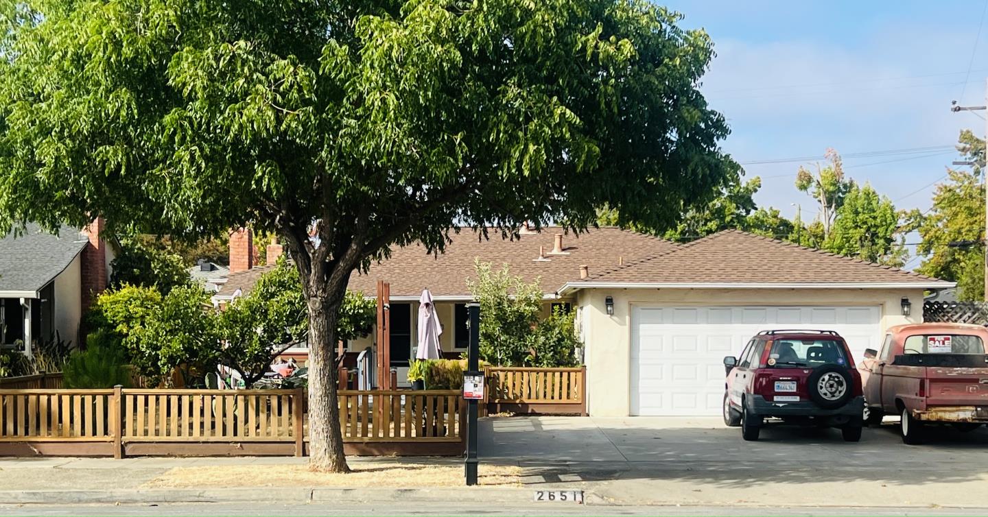 a front view of a house with a garden and tree