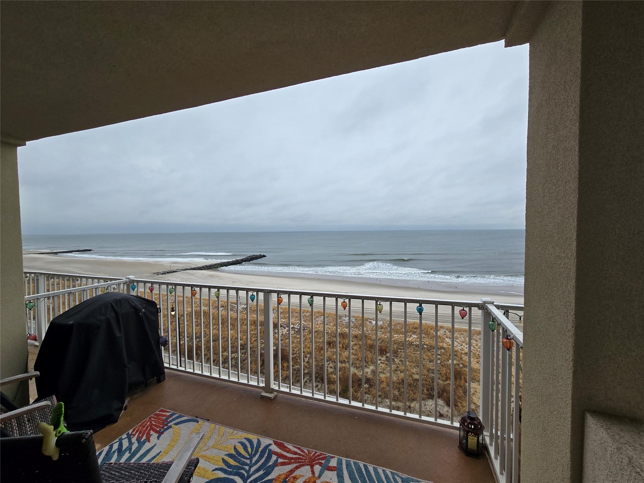 Balcony with a water view, grilling area, and a view of the beach