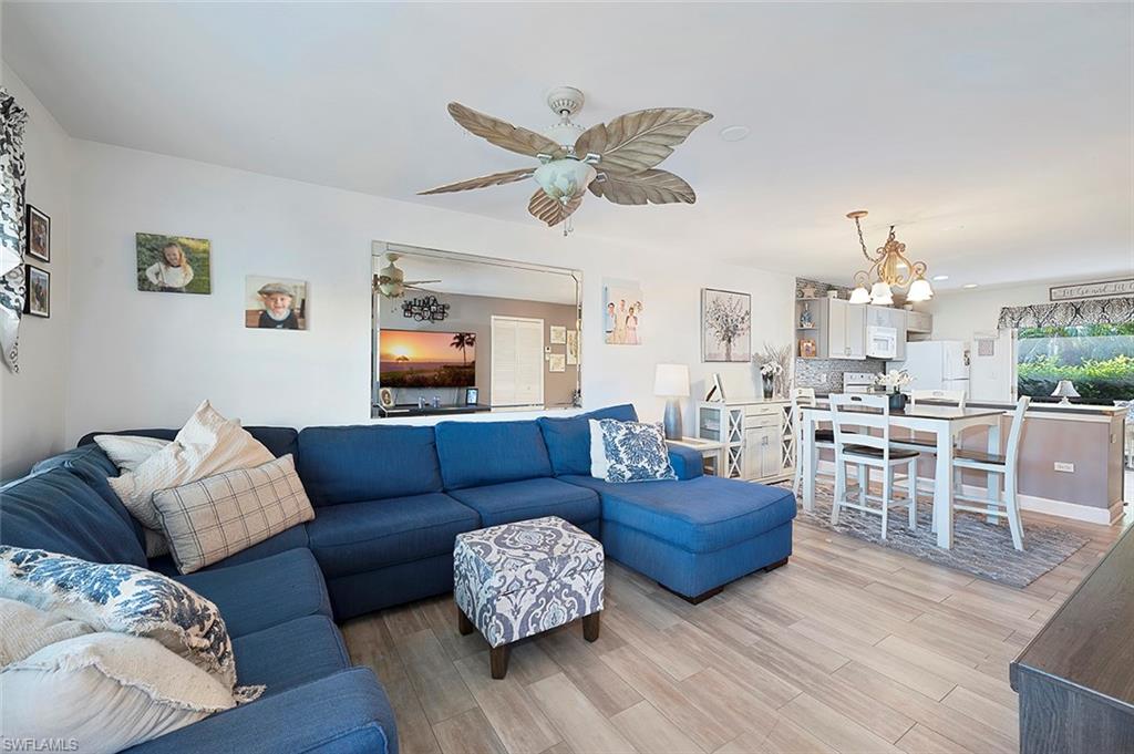 Living room featuring light wood-type flooring and ceiling fan with notable chandelier