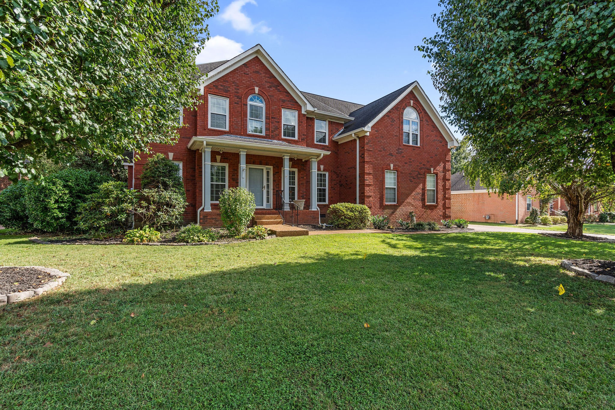 a front view of a house with a yard and trees