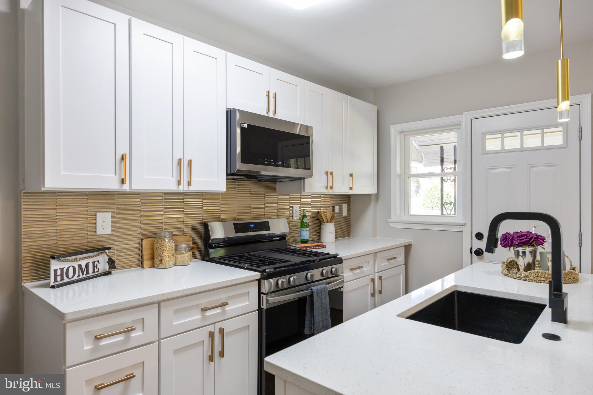 a kitchen with stainless steel appliances a stove a sink a microwave and white cabinets