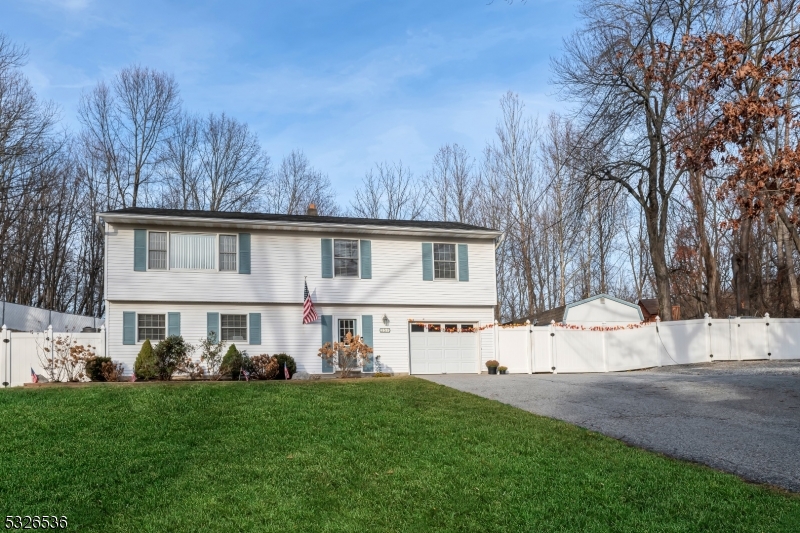 a view of house with yard and trees in the background