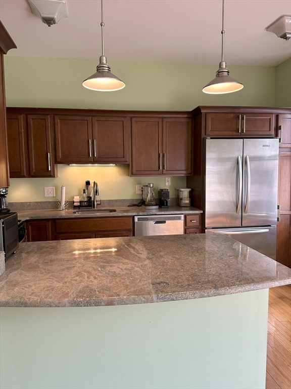 a kitchen with kitchen island granite countertop a sink a counter top space cabinets and stainless steel appliances