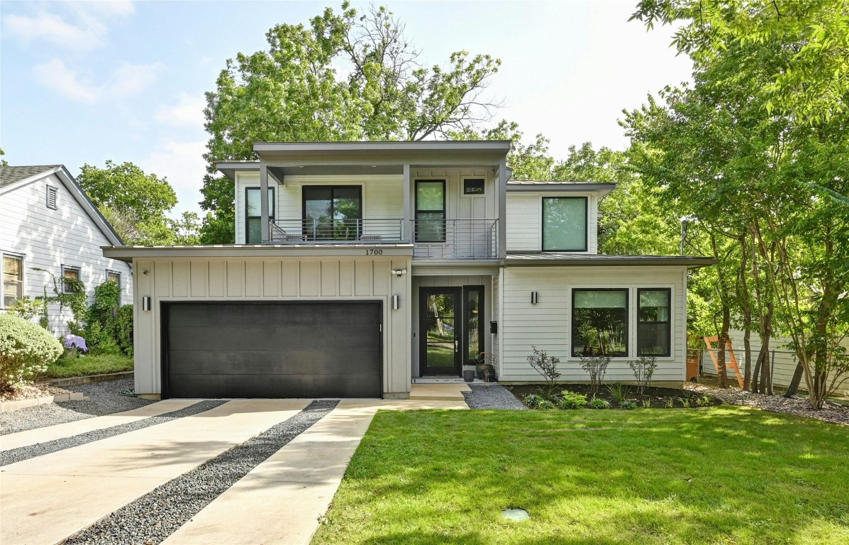 a front view of a house with a garden and trees