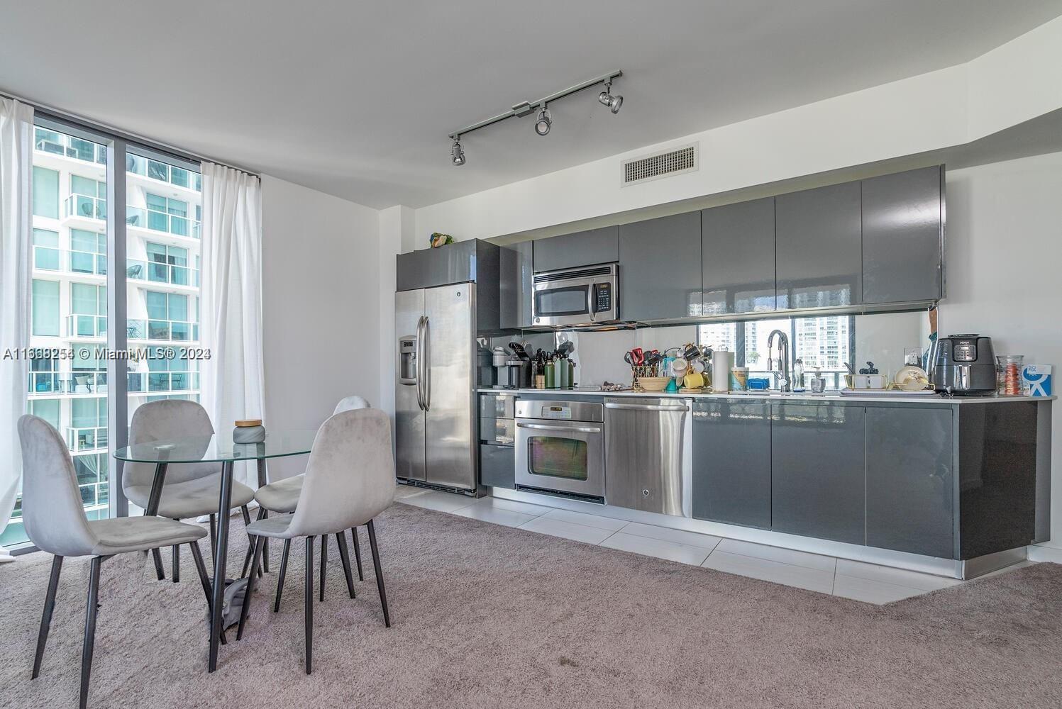 a kitchen with granite countertop stainless steel appliances a table and chairs in it