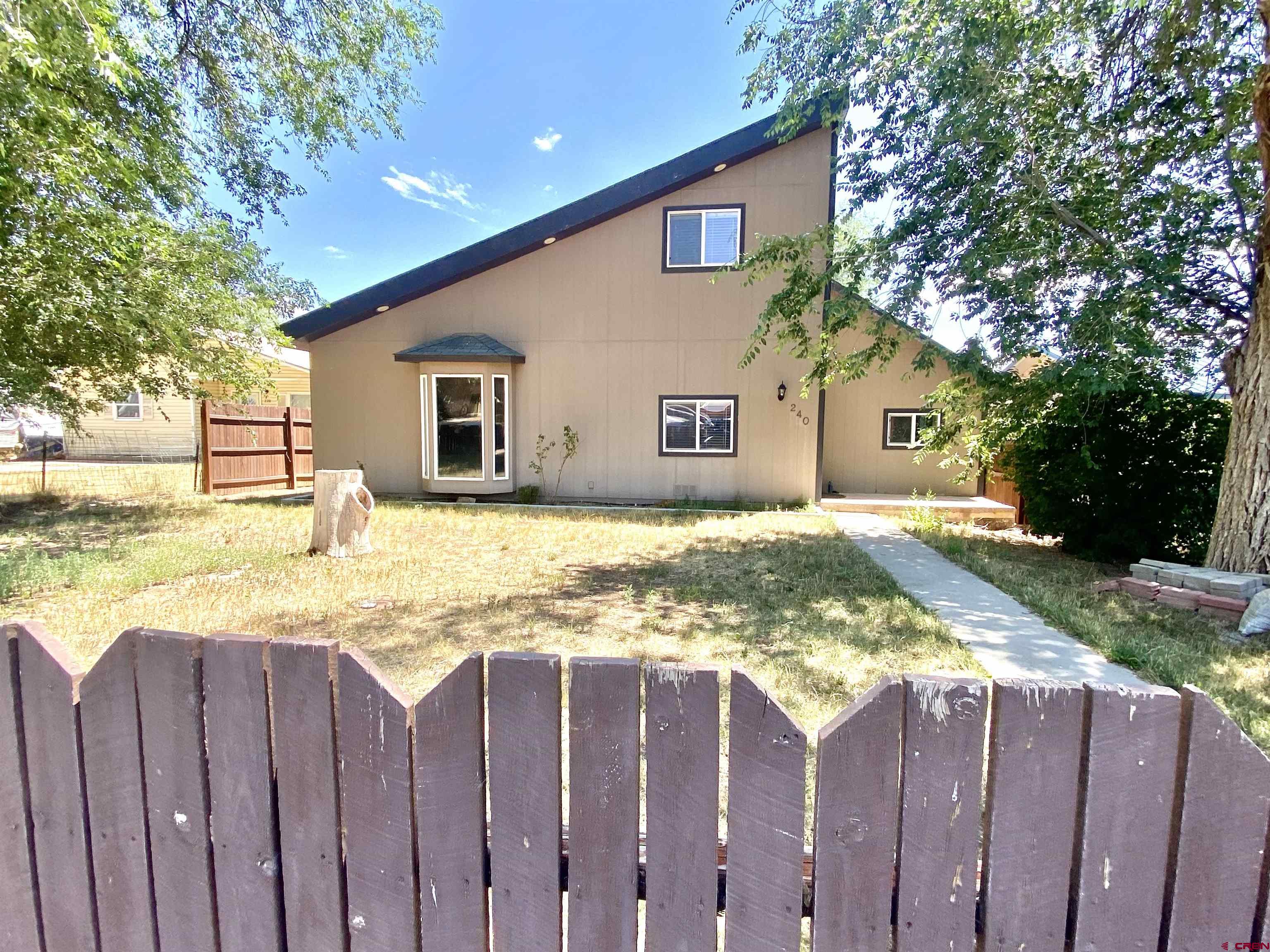 a view of a house with wooden fence next to a yard