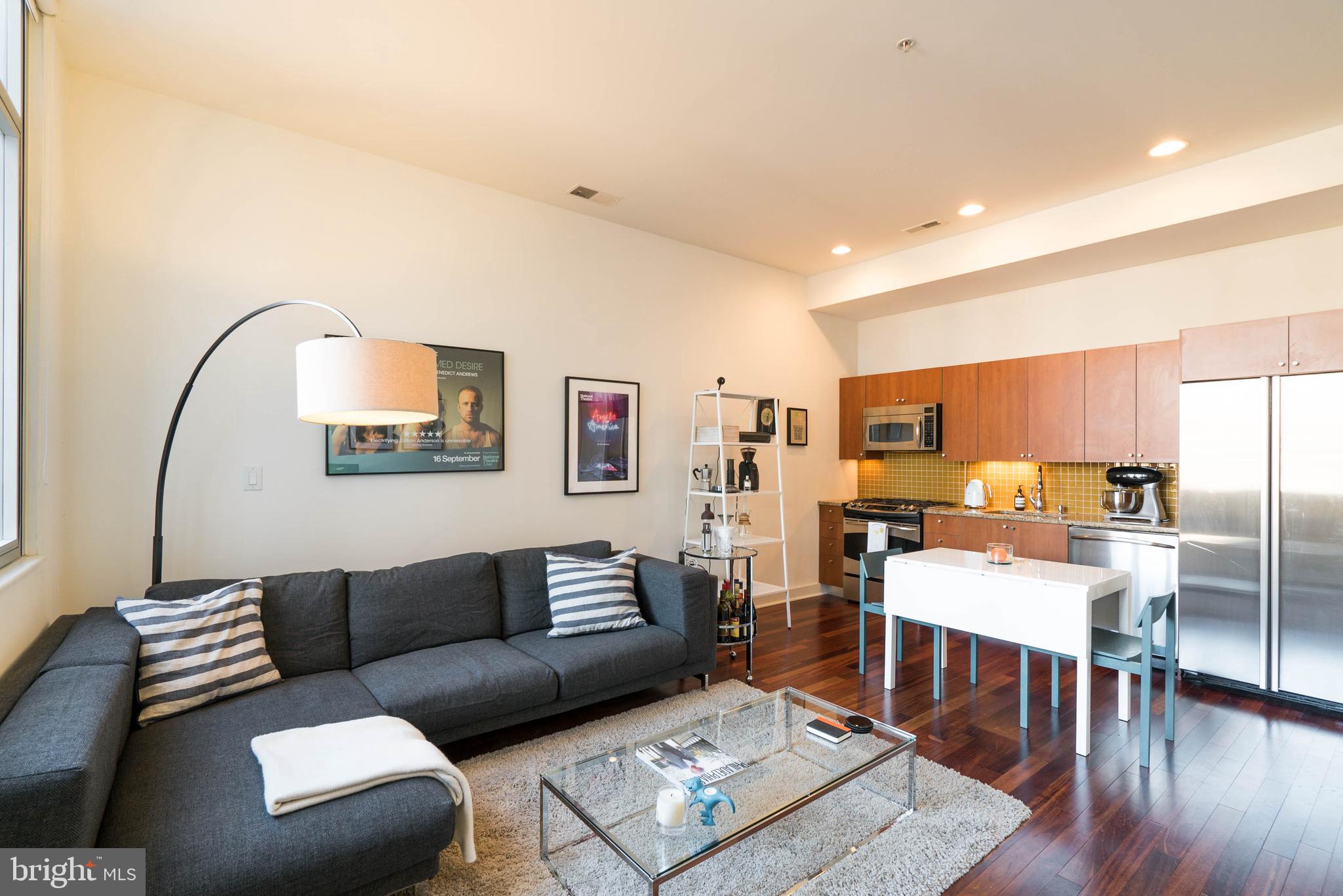 a living room with furniture kitchen view and a wooden floor