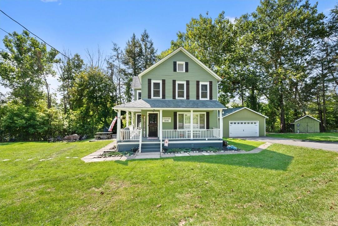 Country-style home with an outbuilding, a garage, a front yard, and covered porch