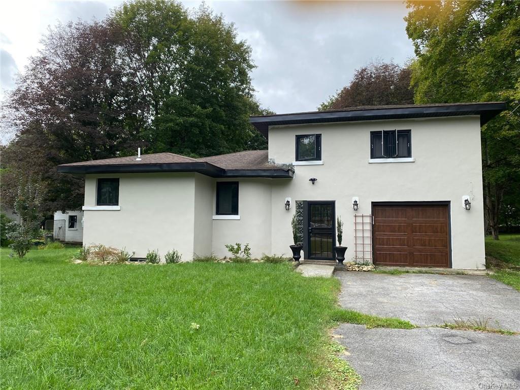 View of front of property featuring a garage and a front lawn