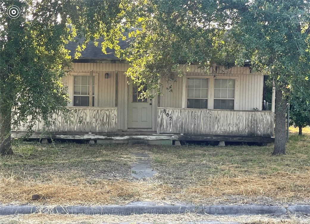 a view of a house with a small yard and large tree