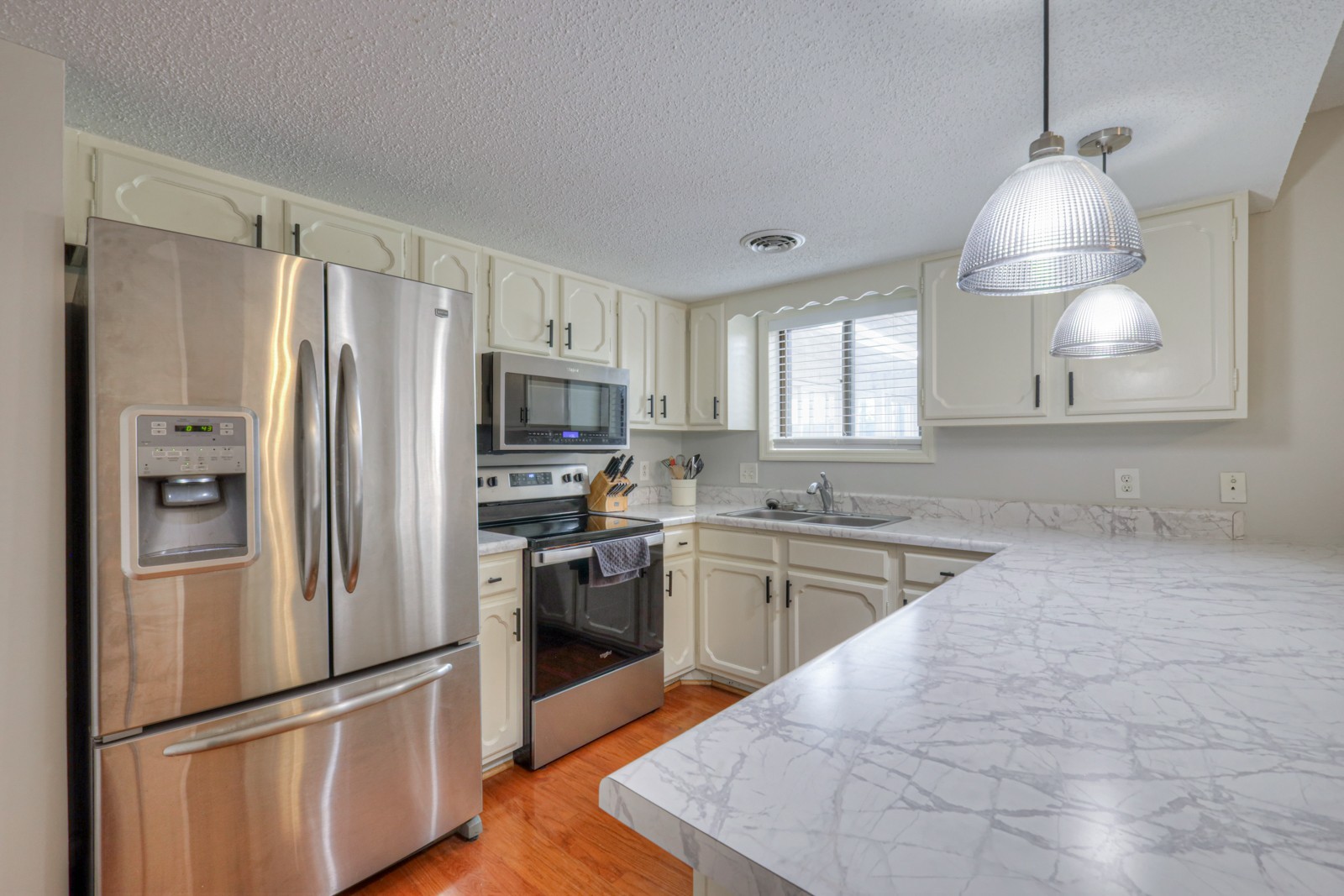 a kitchen with granite countertop stainless steel appliances a refrigerator cabinets and wooden floor