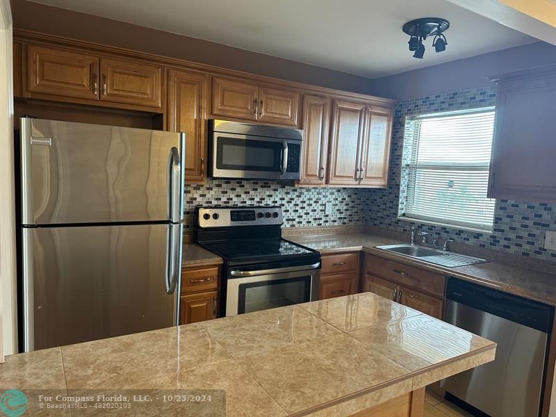 a kitchen with stainless steel appliances granite countertop a refrigerator stove top oven and sink