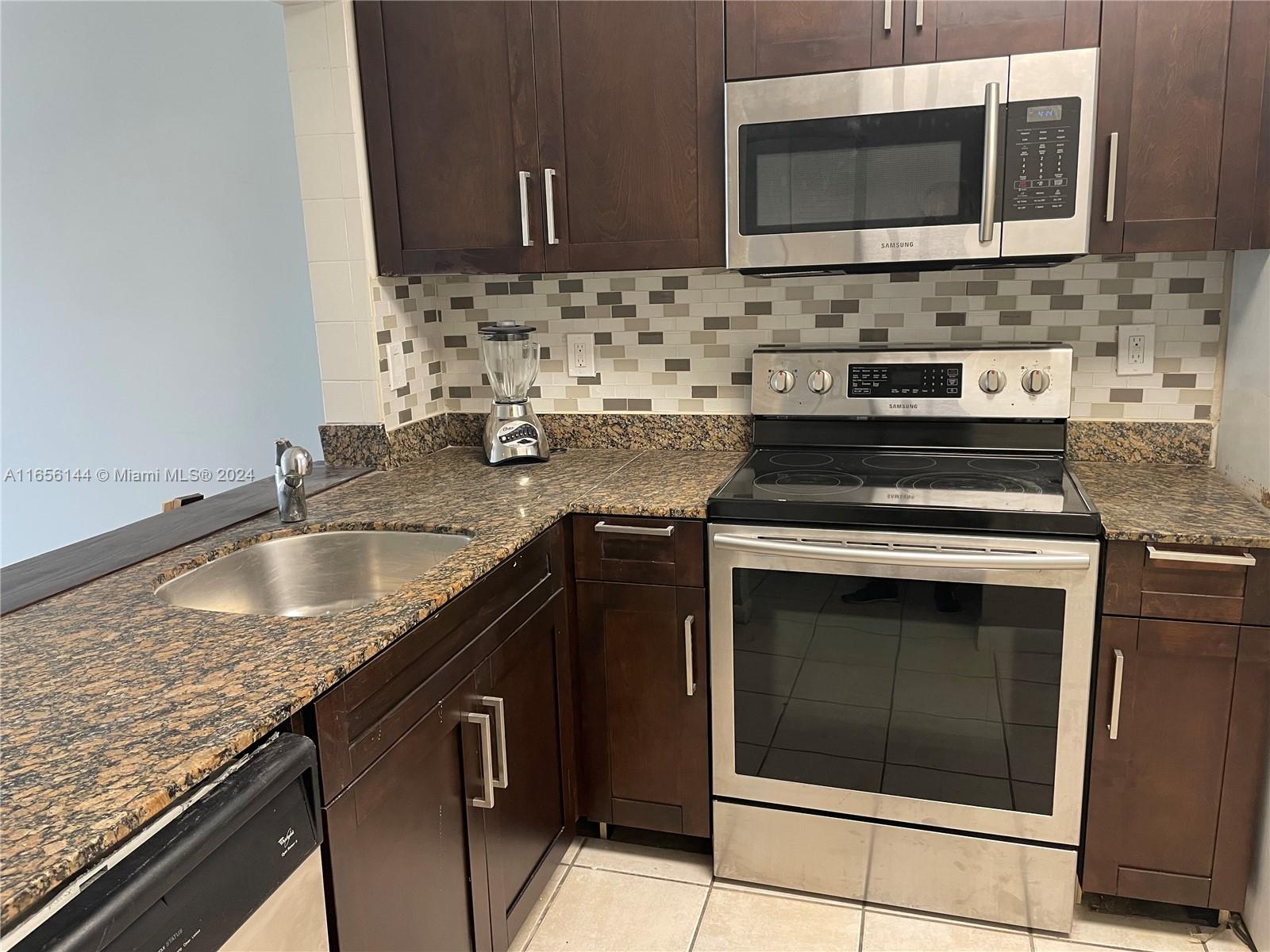 a kitchen with granite countertop a sink stove and microwave