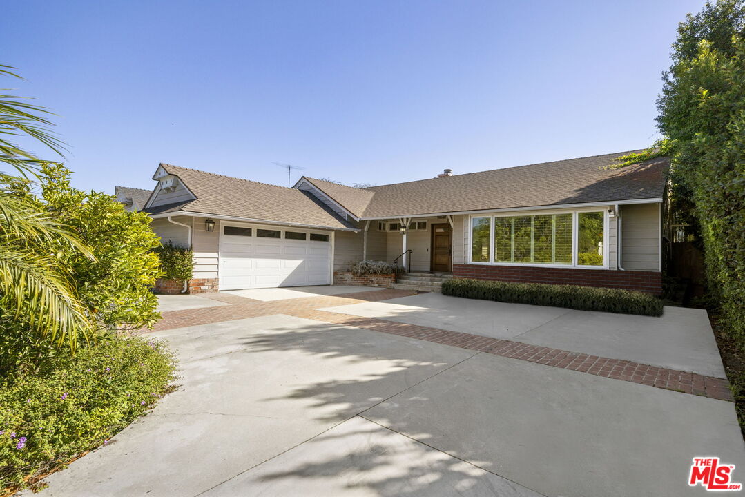 a front view of a house with a big yard and potted plants