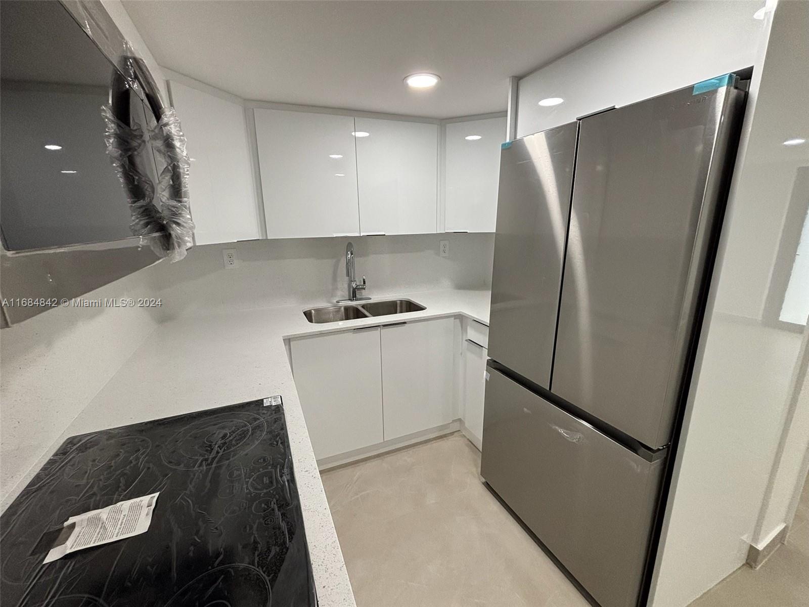 a kitchen with stainless steel appliances a refrigerator a sink and white cabinets