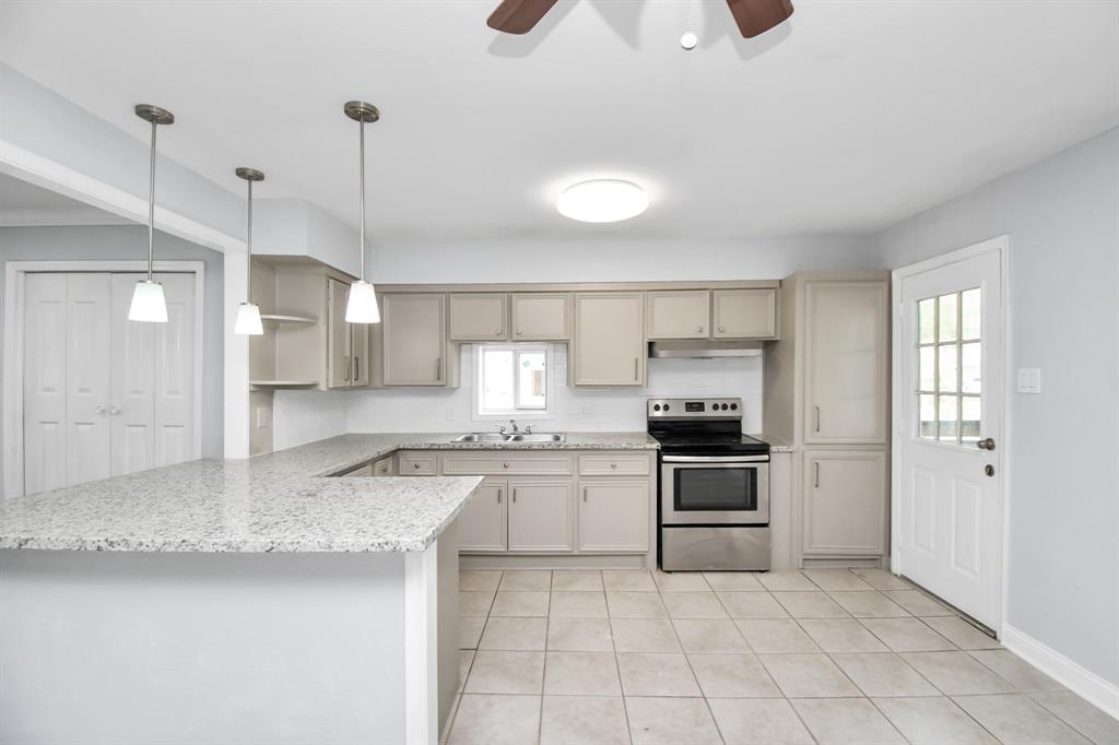 a kitchen with granite countertop a stove a sink and a refrigerator