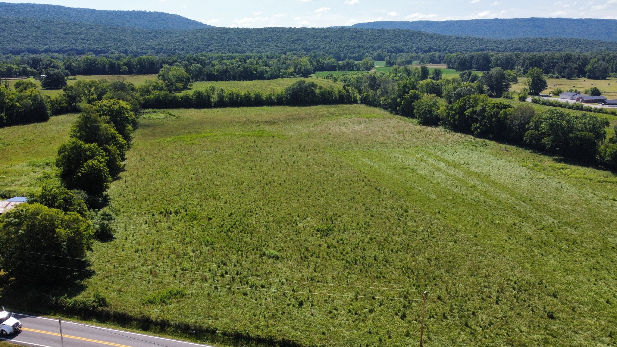 a view of a lush green field with mountains in the background