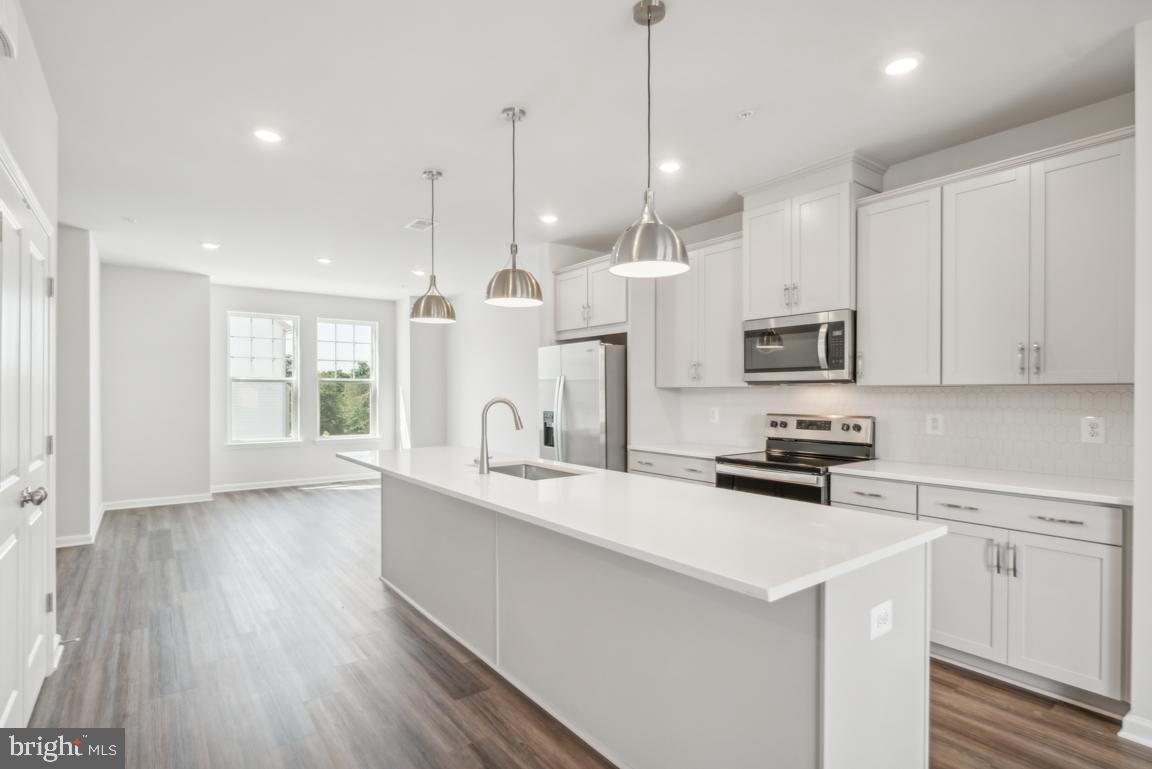 a large kitchen with stainless steel appliances kitchen island granite countertop a stove a sink a center island a refrigerator and a wooden floor