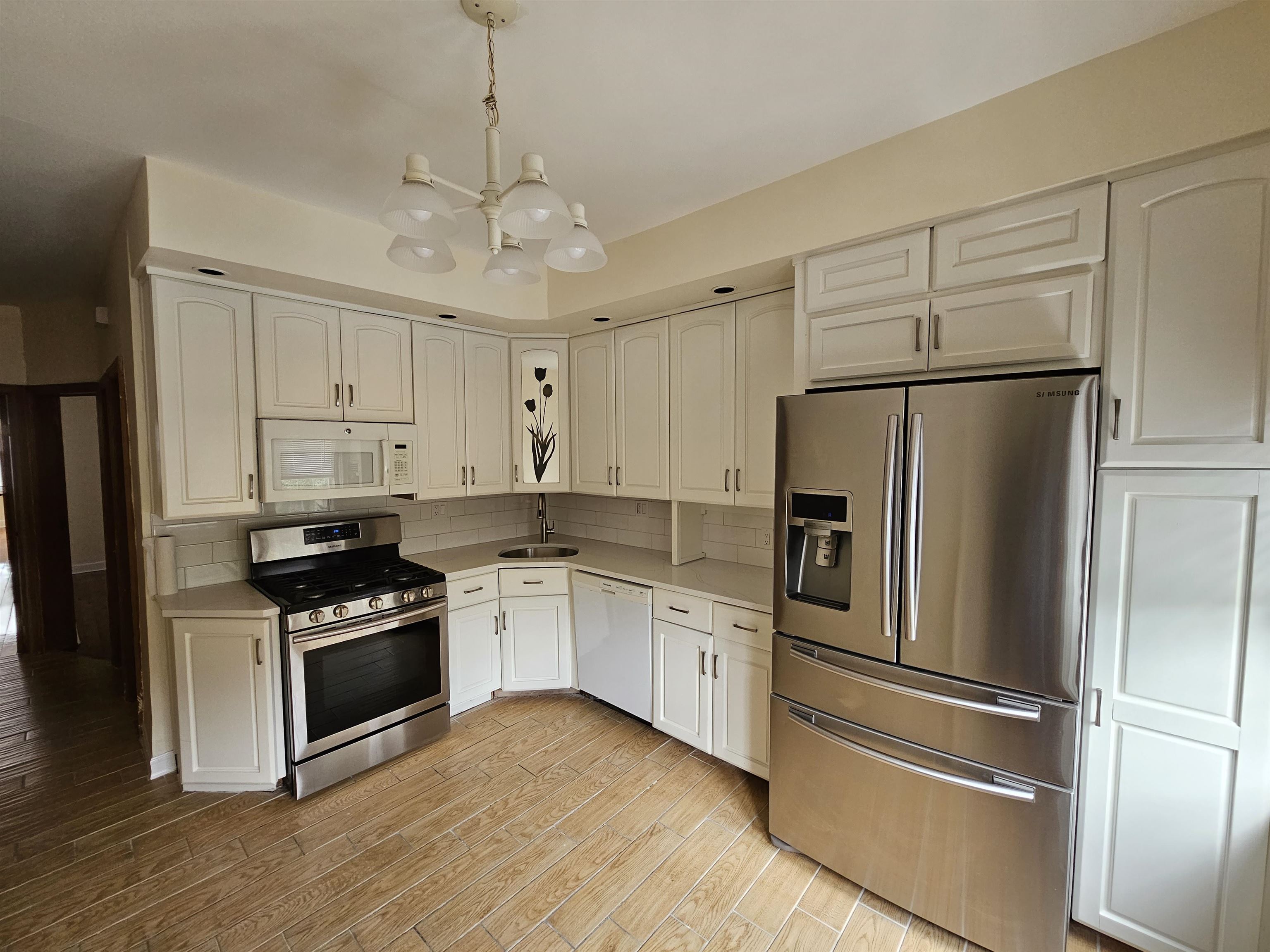 a kitchen with stainless steel appliances granite countertop a refrigerator a stove a sink and white cabinets