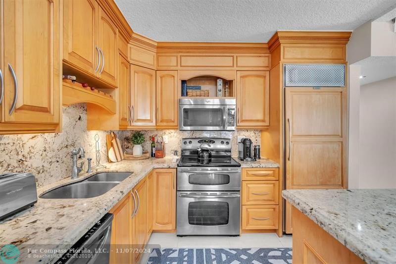 a kitchen with stainless steel appliances granite countertop a sink stove and refrigerator