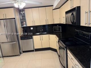 a kitchen with granite countertop a refrigerator a sink and white cabinets