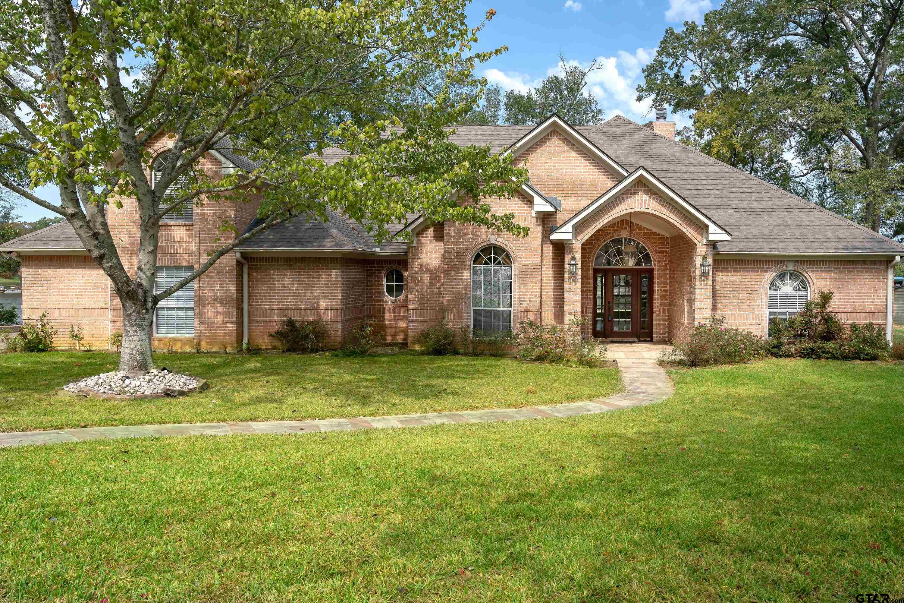 a front view of a house with a garden and trees