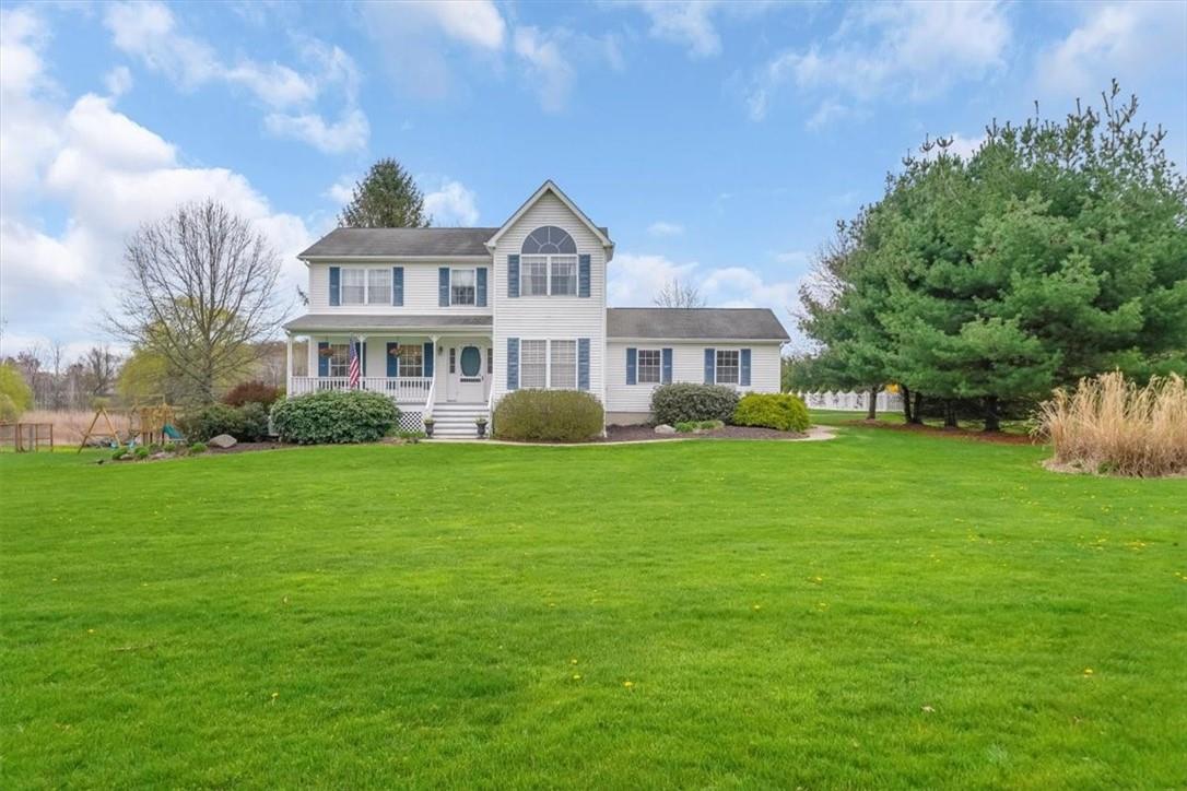 Colonial-style house featuring a porch and a front yard