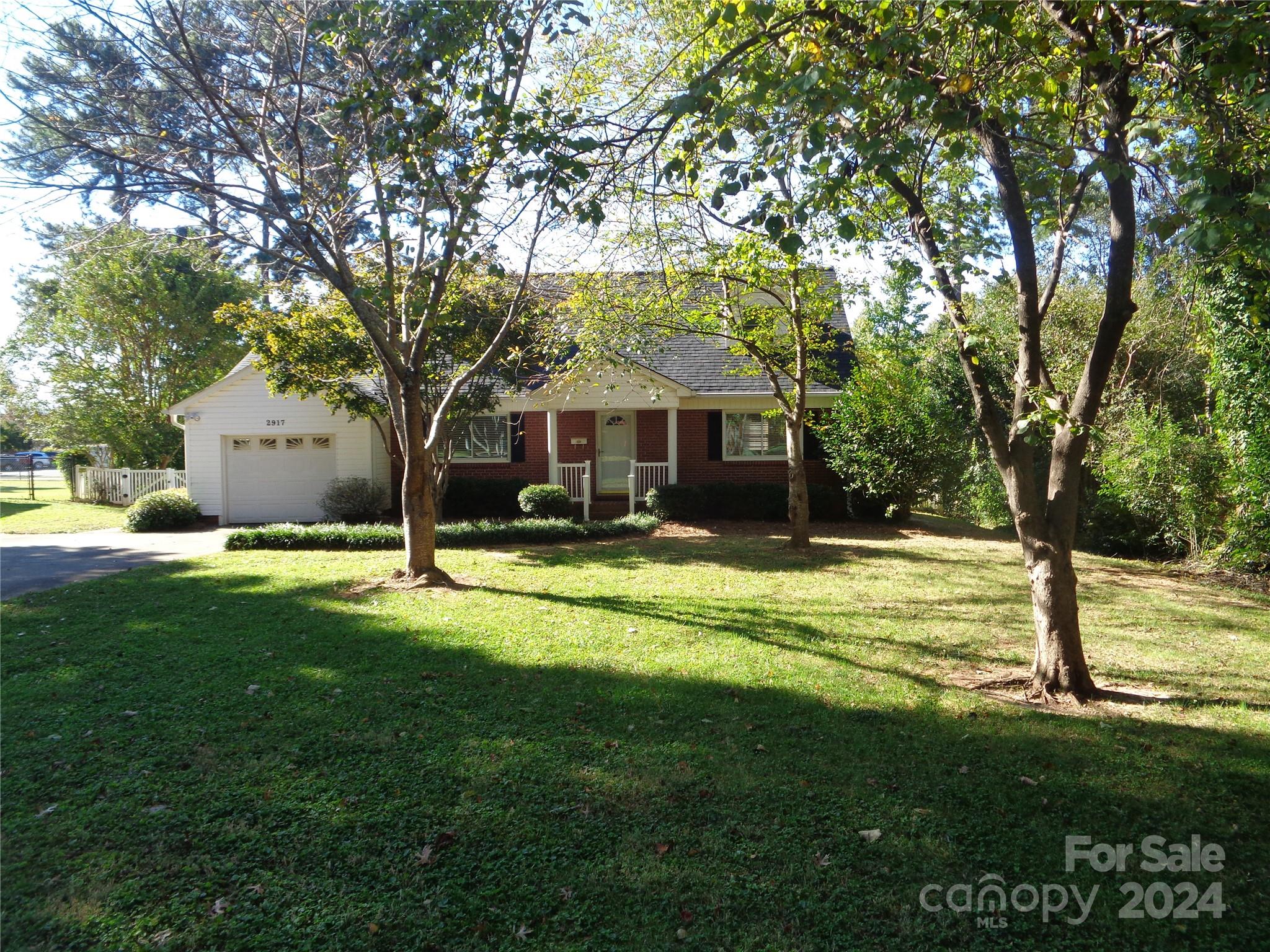 a view of a house with a big yard and large trees