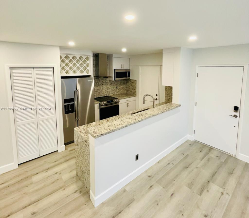 a kitchen with a refrigerator a stove and a sink with wooden floor