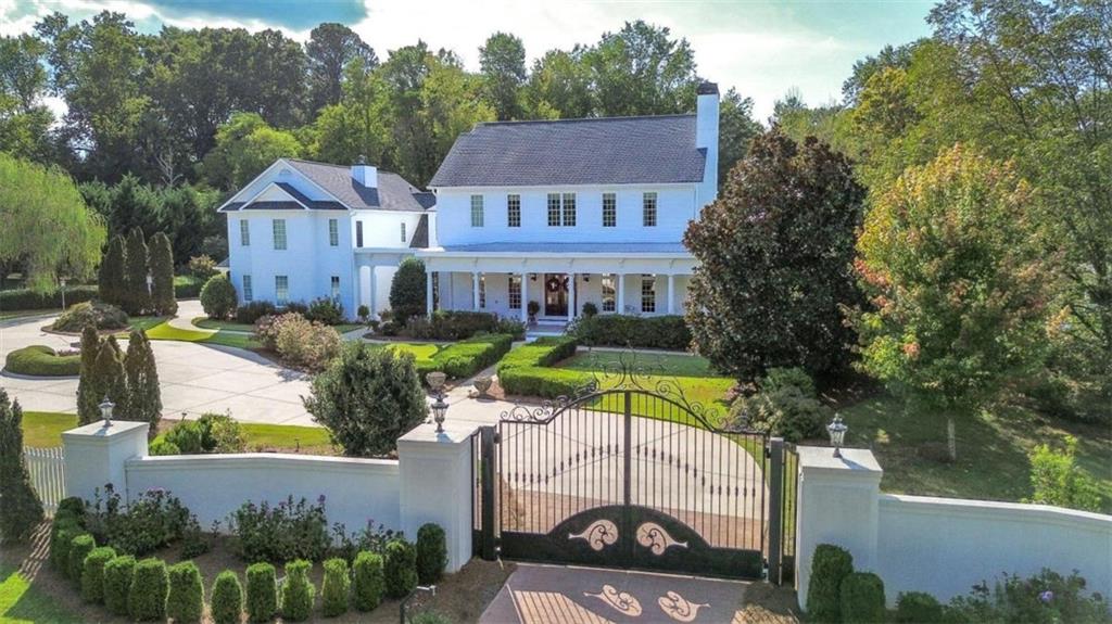 an aerial view of a house with swimming pool and large trees