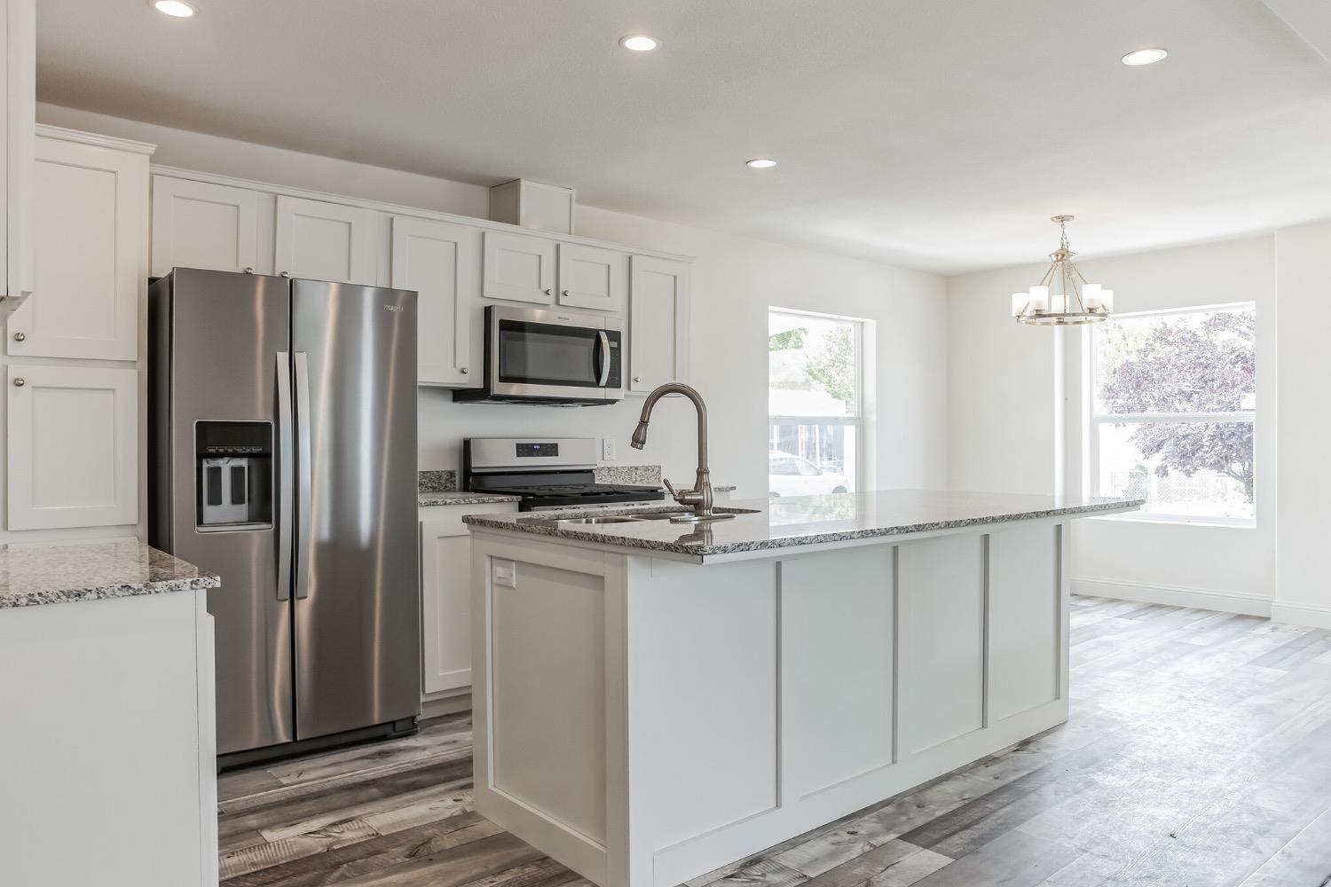 a kitchen with granite countertop a refrigerator stove and microwave