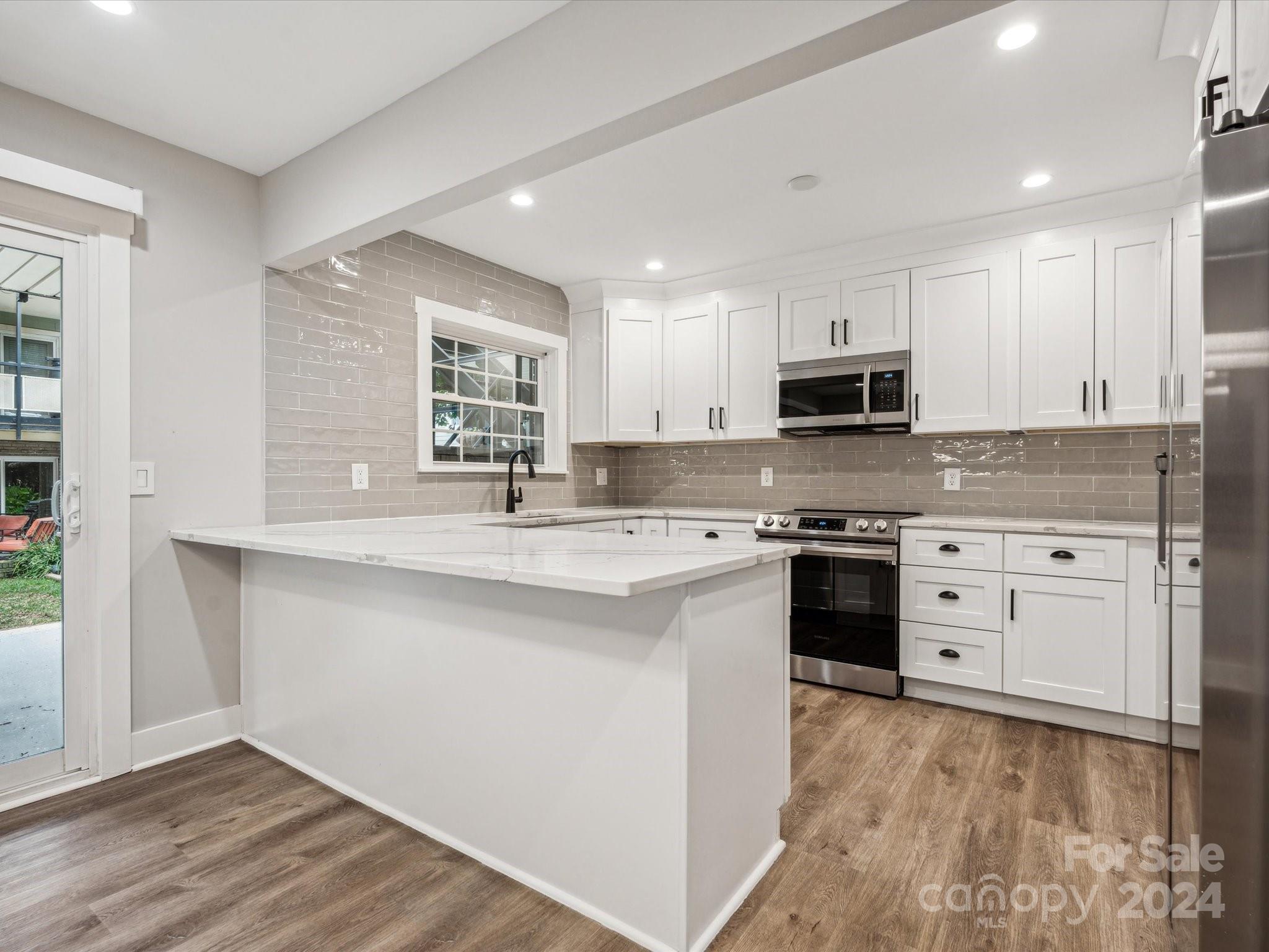 a kitchen with kitchen island granite countertop white cabinets and stainless steel appliances