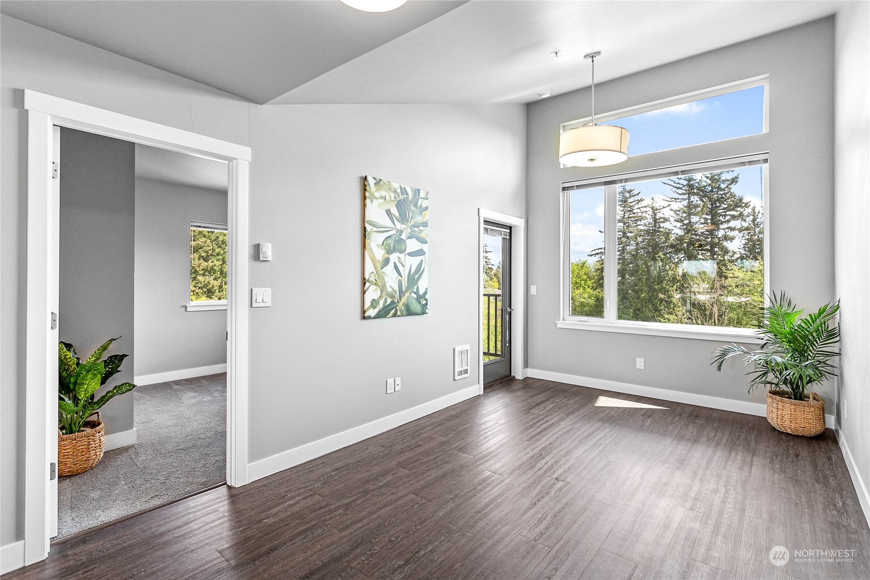 a view of an empty room with a window and wooden floor