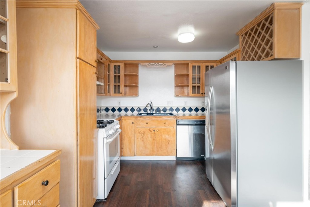 a view of a kitchen with a sink and dishwasher a refrigerator with wooden floor