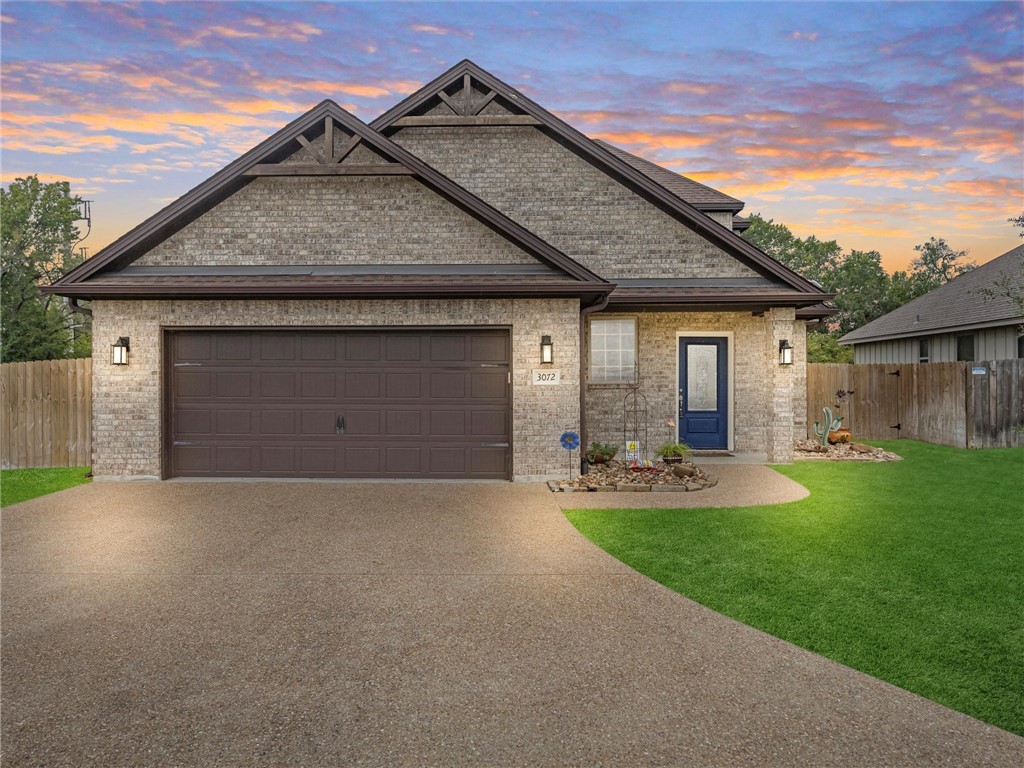 View of front facade with a garage and a yard