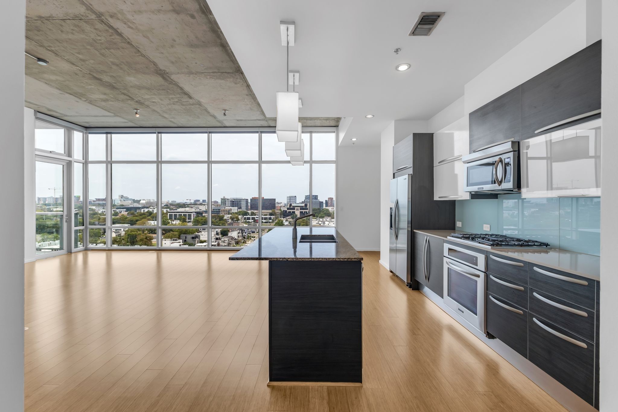 a large kitchen with stainless steel appliances granite countertop a large window and a wooden floor