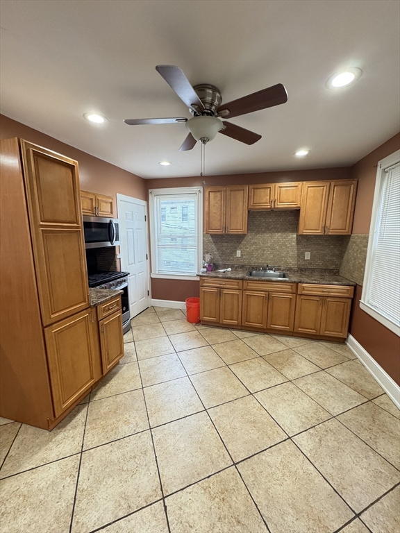 a kitchen with granite countertop a refrigerator a sink a stove top oven and cabinets