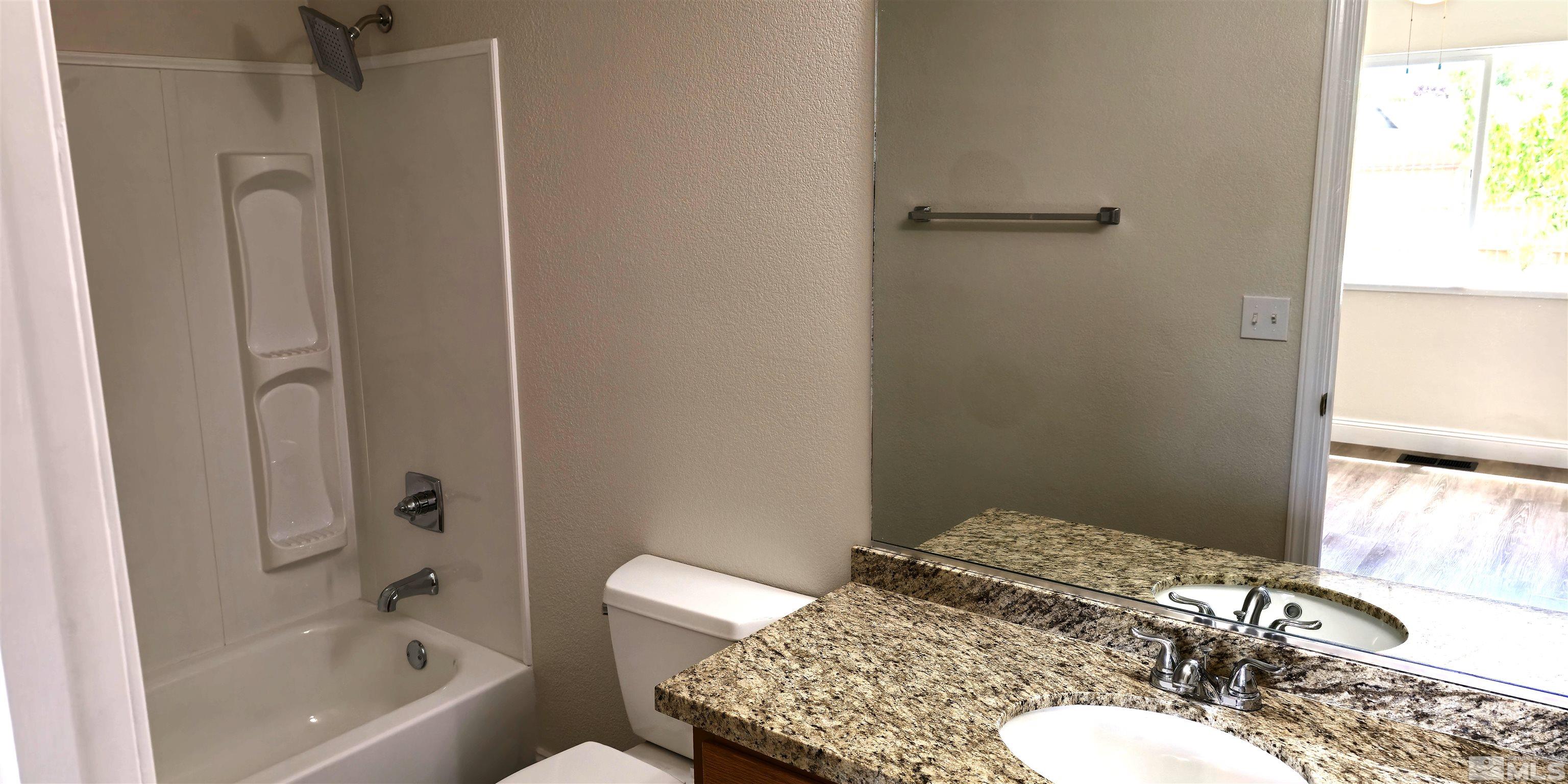 a bathroom with a granite countertop sink toilet and shower