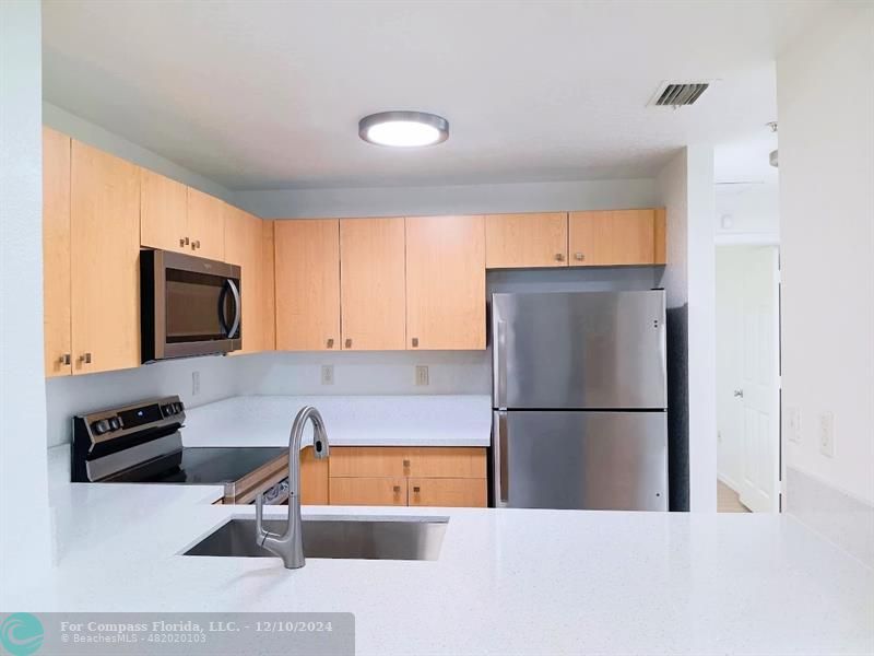 a kitchen with stainless steel appliances granite countertop a refrigerator and a sink